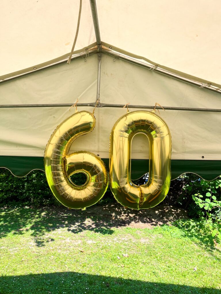 Goldene 60 Luftballons unter Zelt.