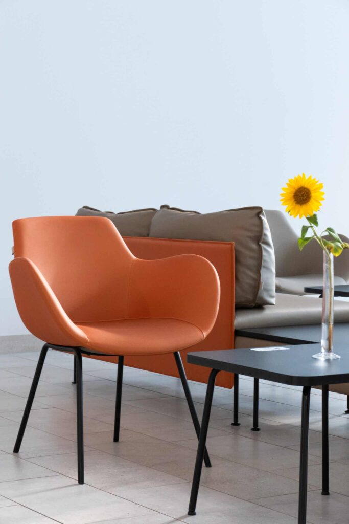 Moderner Stuhl, Couch und Sonnenblume in Vase.