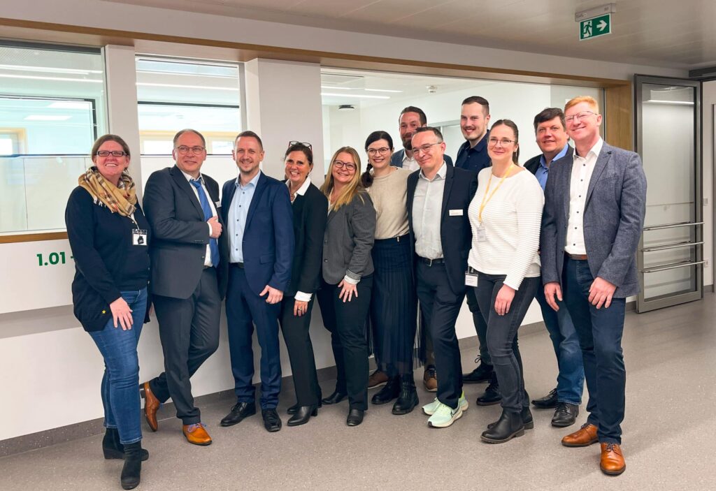 Gruppe von Menschen in Bürogebäude lächelt.