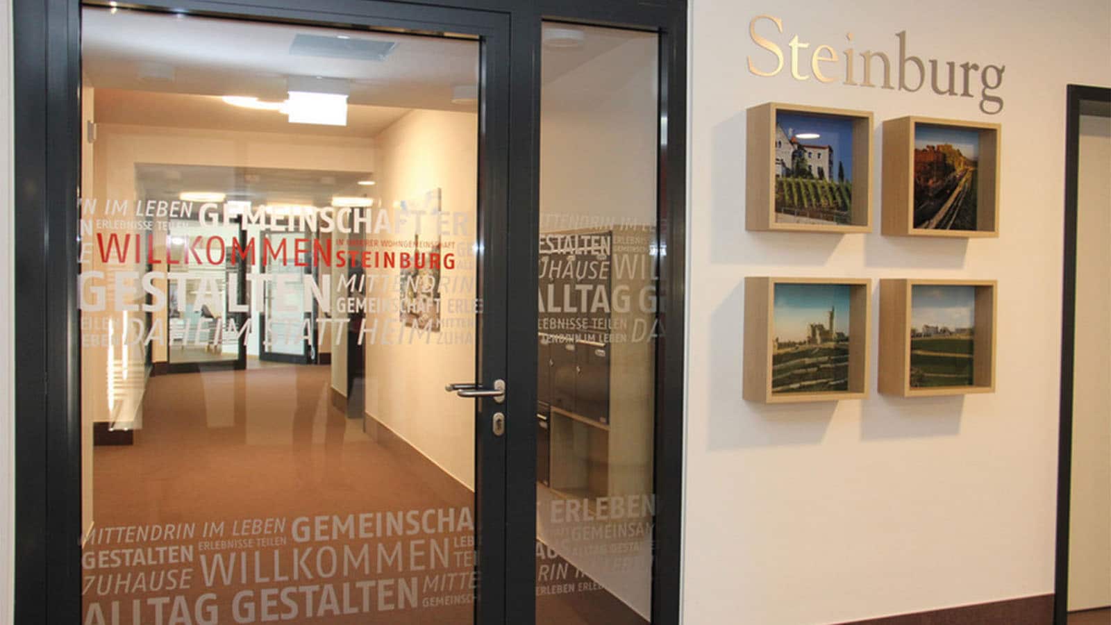 Büroeingang mit Steinburg-Bildergalerie und Glaswandtexten.