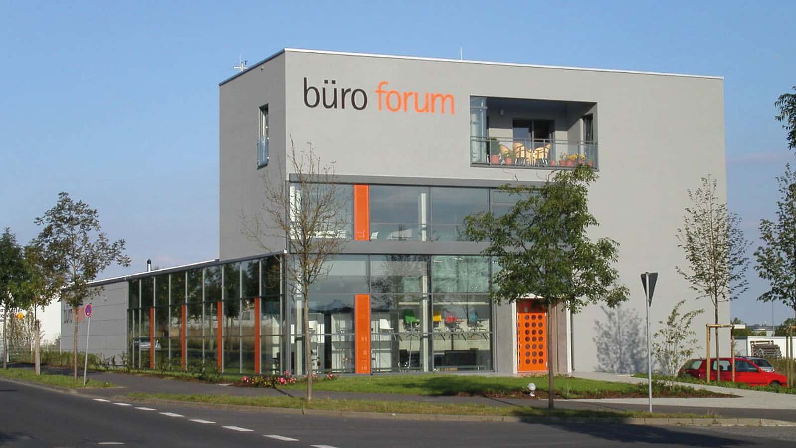 Modernes Bürogebäude mit Glasfassade und orange Akzenten.
