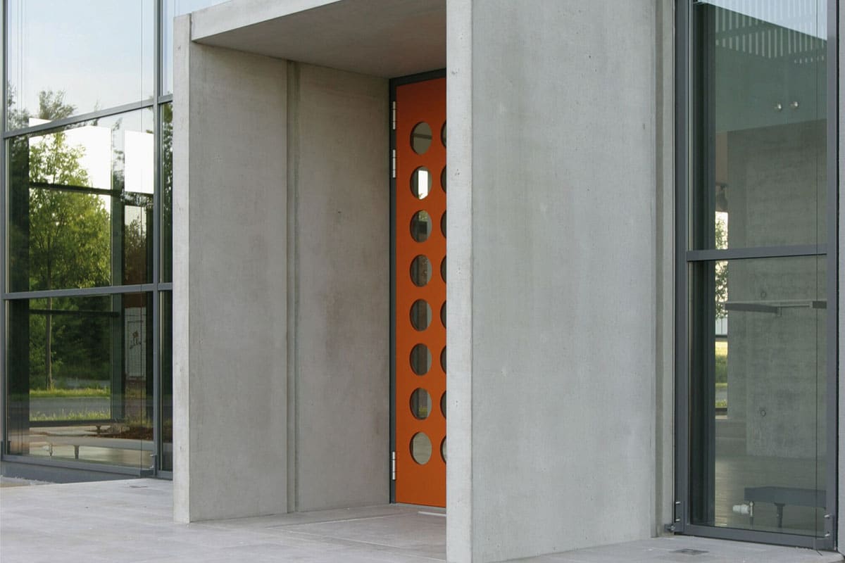 Moderne orange Tür mit Betonrahmen