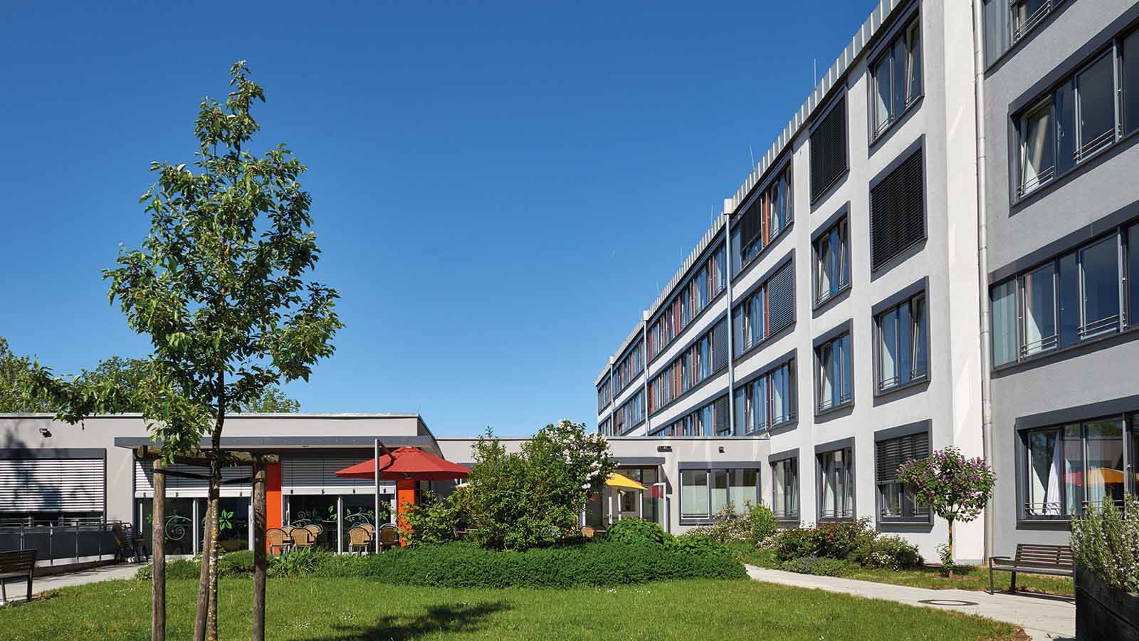 Grüner Innenhof eines modernen Gebäudes bei sonnigem Wetter.