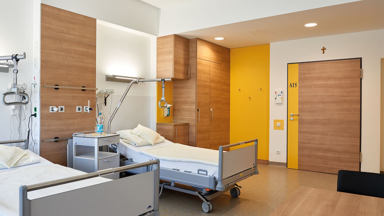 Modernes Krankenhauszimmer mit zwei Betten und Holzmöbeln