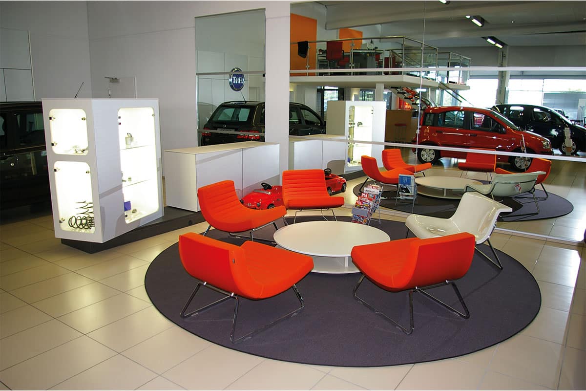 Autohaus-Innenraum mit roten Stühlen und Autos