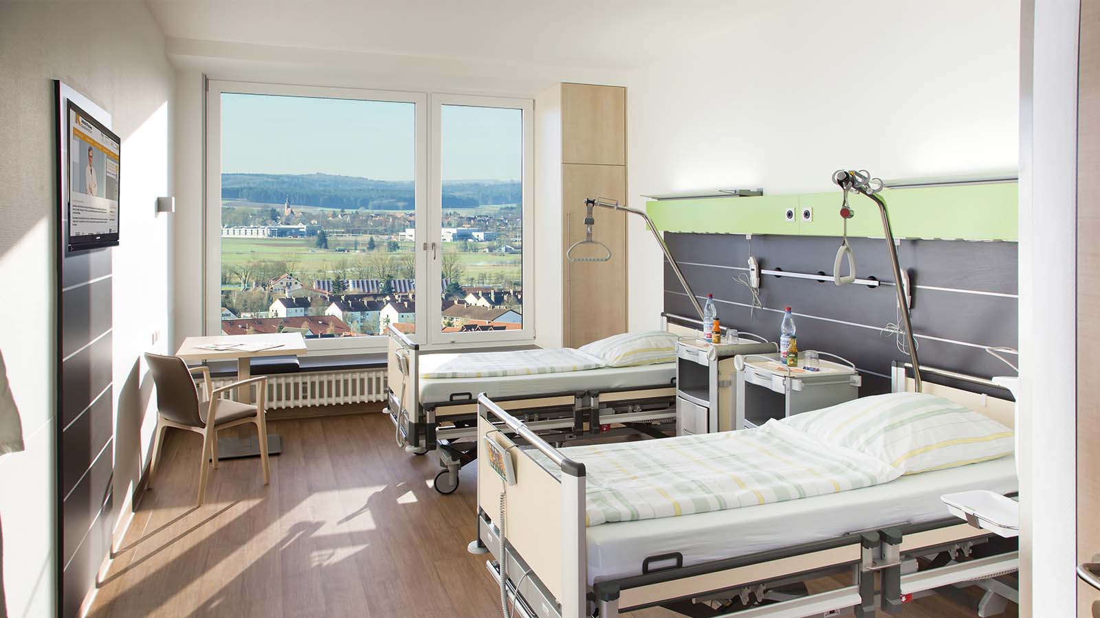 Modernes Krankenhauszimmer mit zwei Betten und Ausblick.