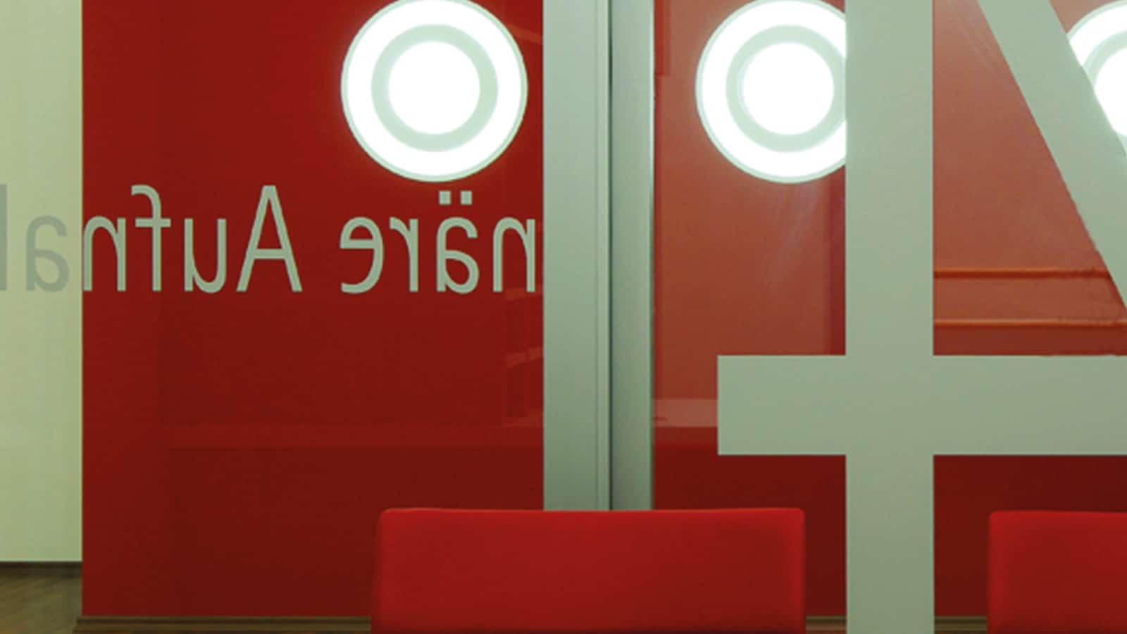 Rotes modernes Wartezimmer mit Glaswänden und Stühlen.