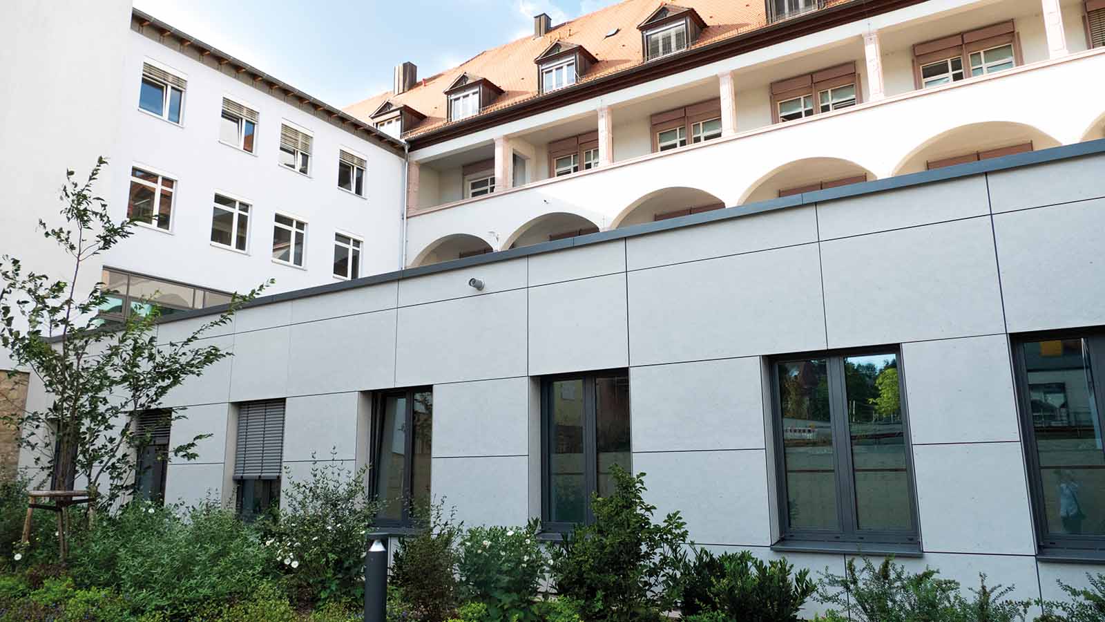 Moderner Gebäudekomplex mit verglasten Fenstern und Pflanzen.