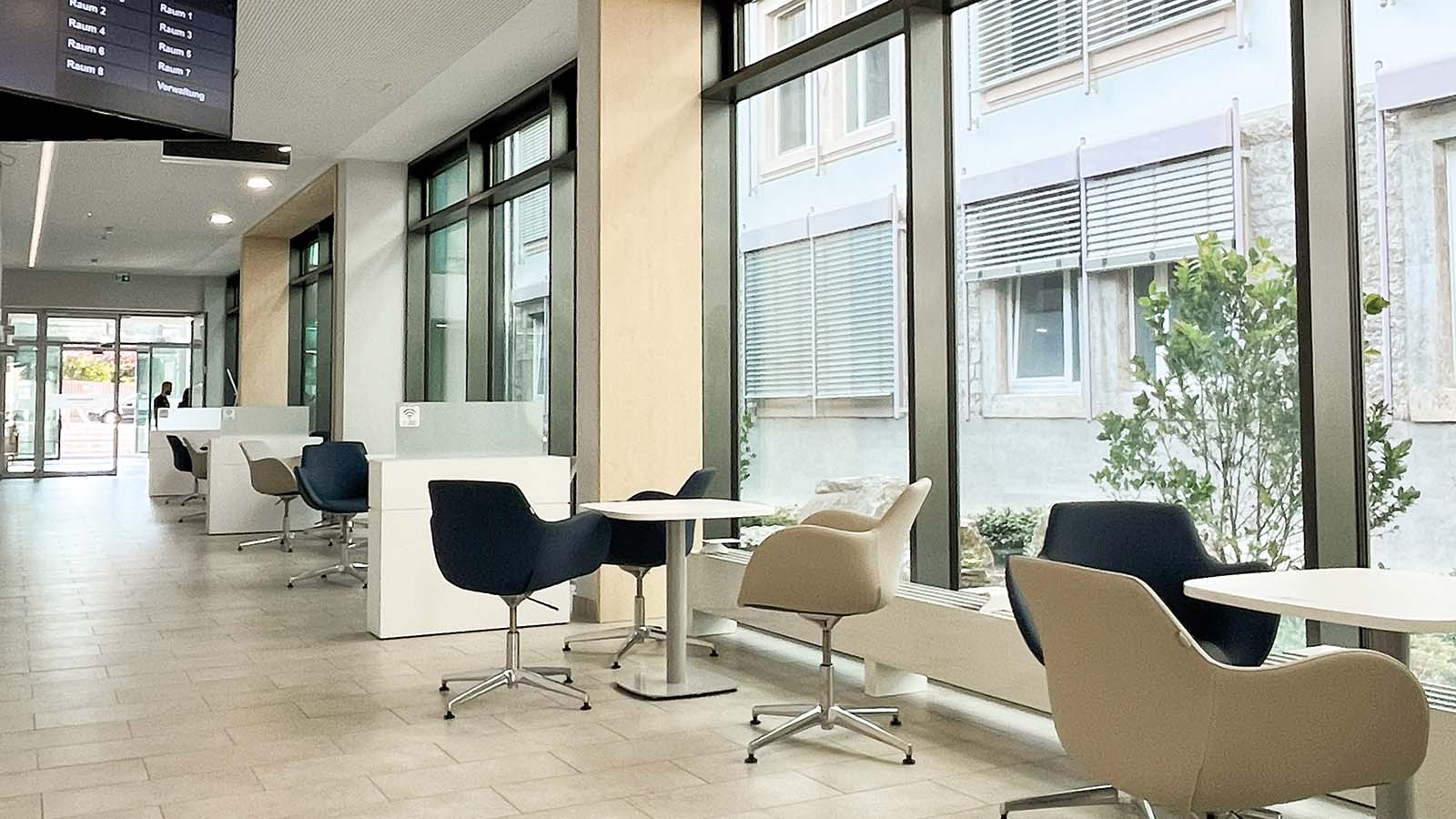Moderner Warteraum mit Stühlen und Tischen, großer Fensteransicht.