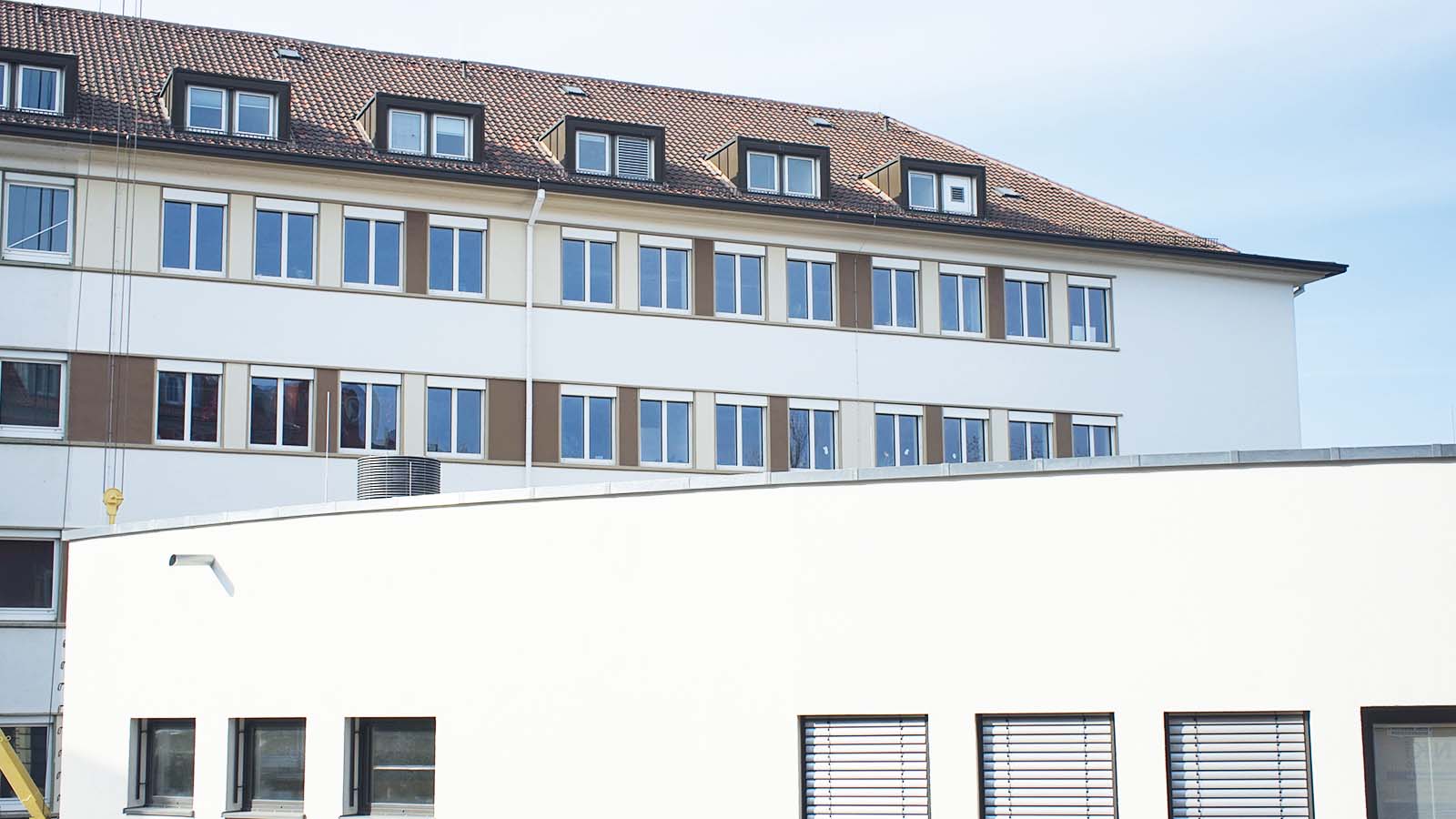 Modernes Gebäude mit vielen Fenstern und weißer Fassade.