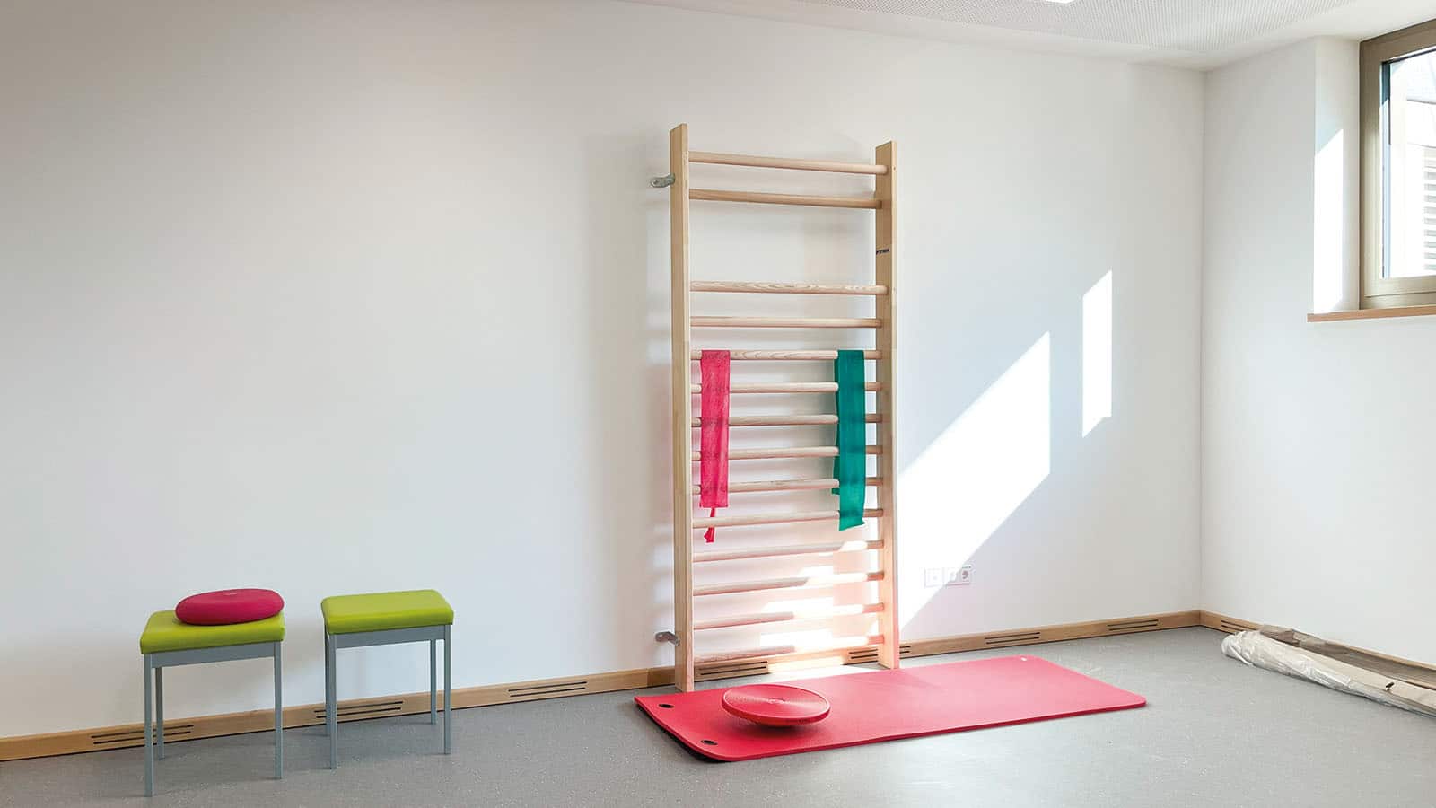 Gymnastikraum mit Sprossenwand und zwei Hockern