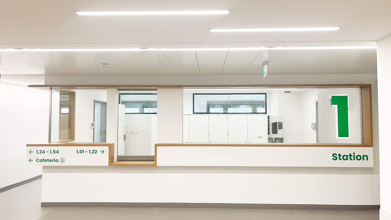 Krankenhausstation mit Wegweiser zu Zimmern und Cafeteria.