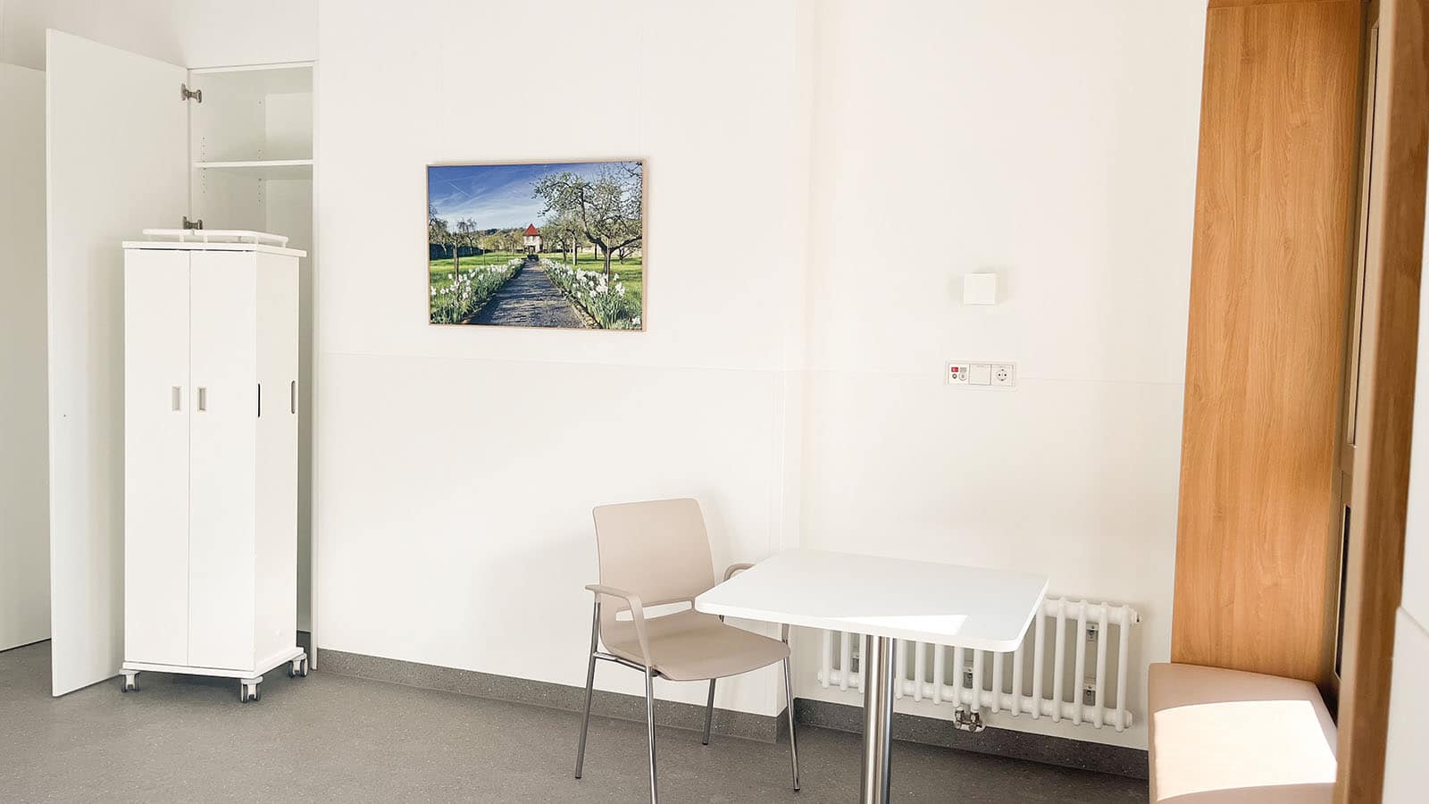 Helle Ecke mit Tisch, Stuhl, Schrank und Bild.