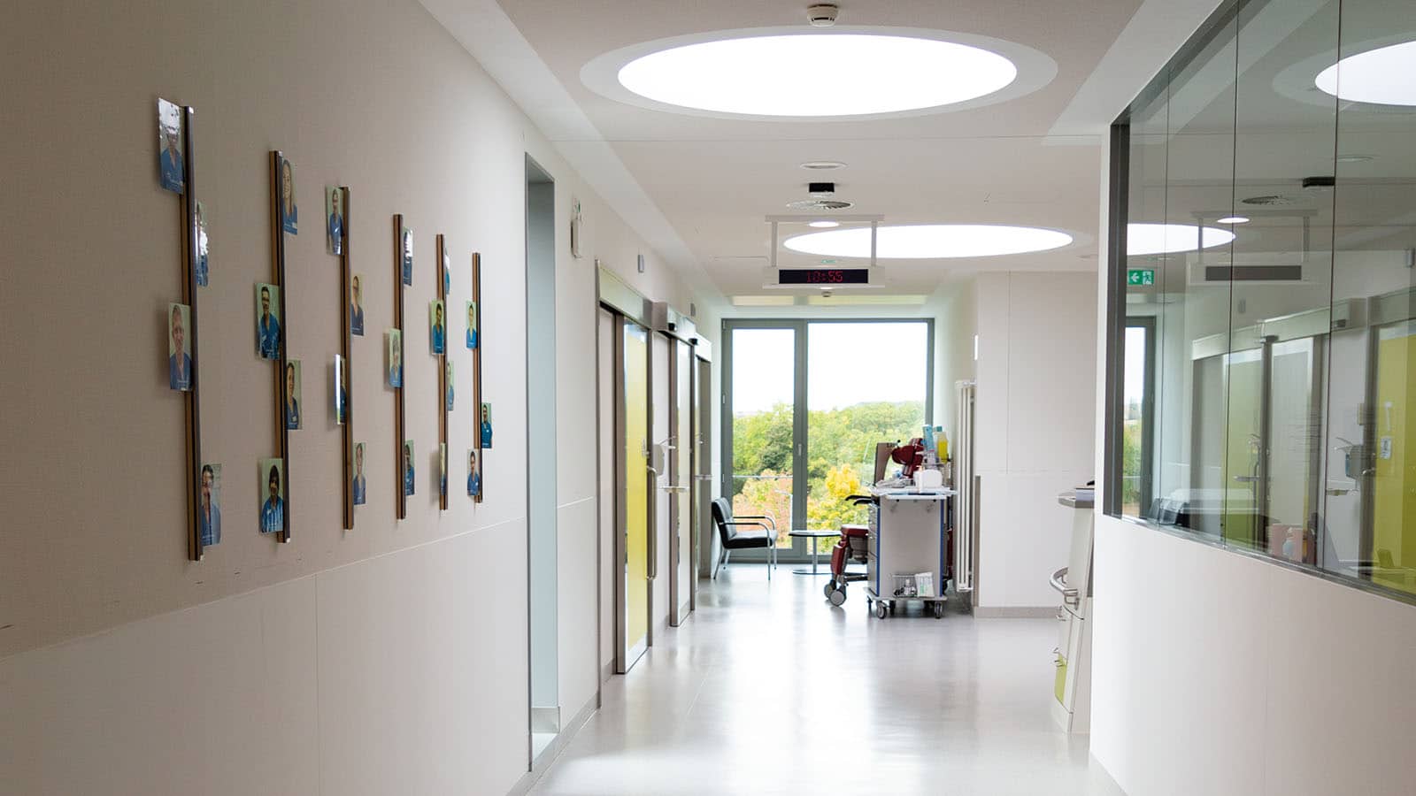 Heller Krankenhausflur mit Wandfotos und Türen