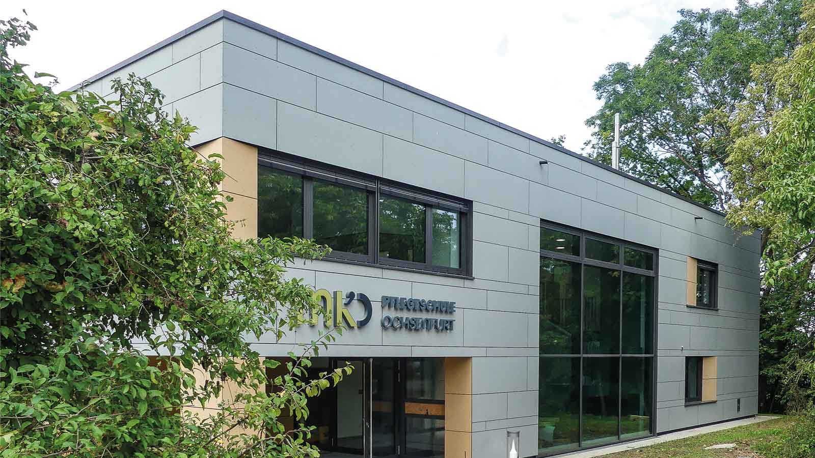 Moderne Architektur mit Glasfront und grüner Umgebung