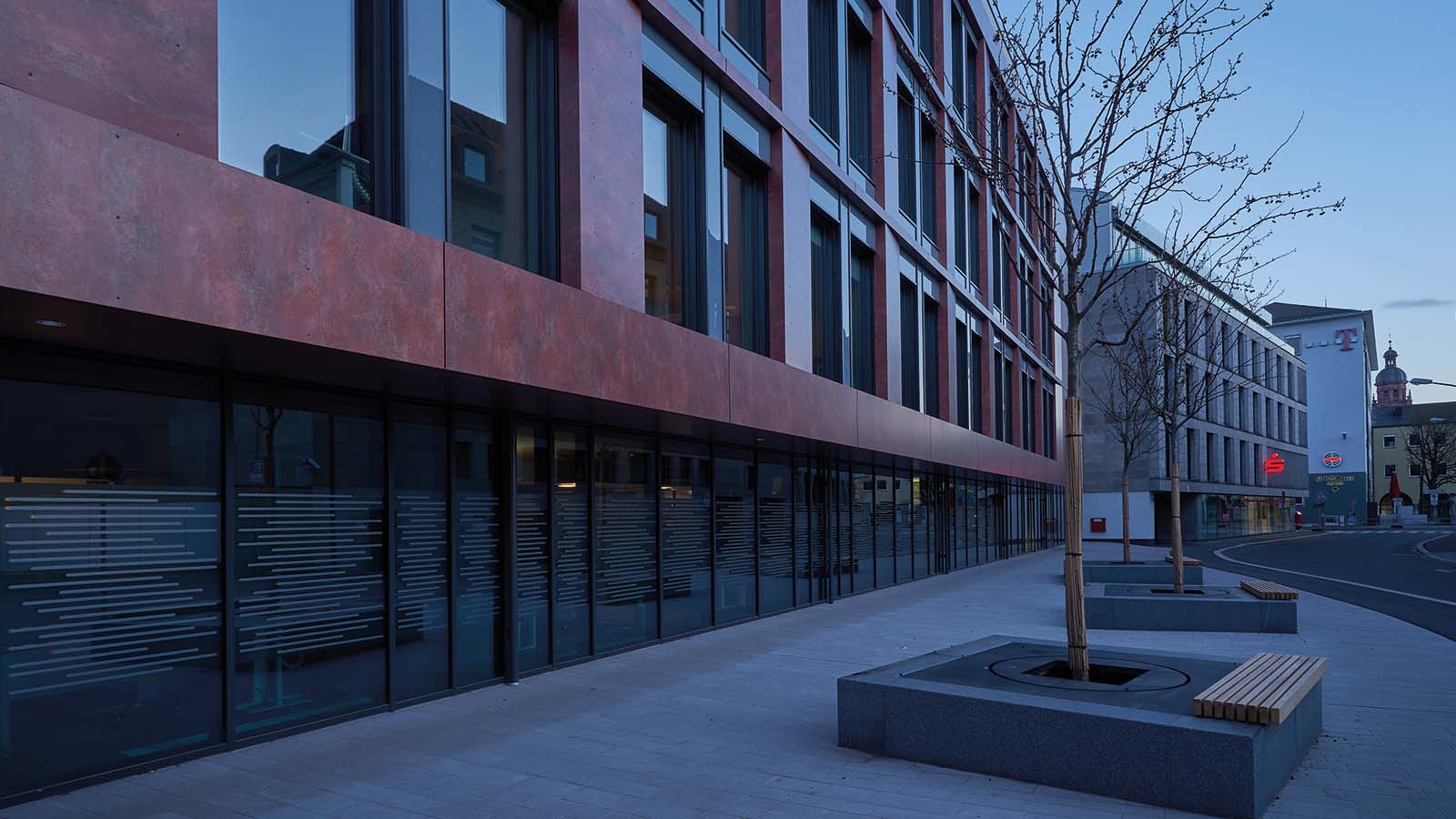 Moderne Fassade und Gehweg mit Bänken und Bäumen