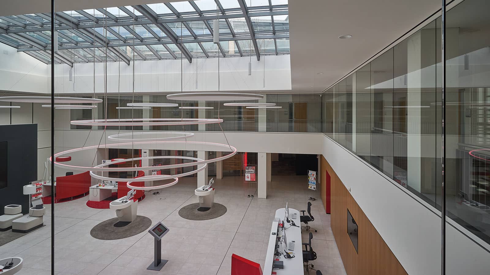 Moderne Bürolandschaft mit Glasdach und Schreibtischen.