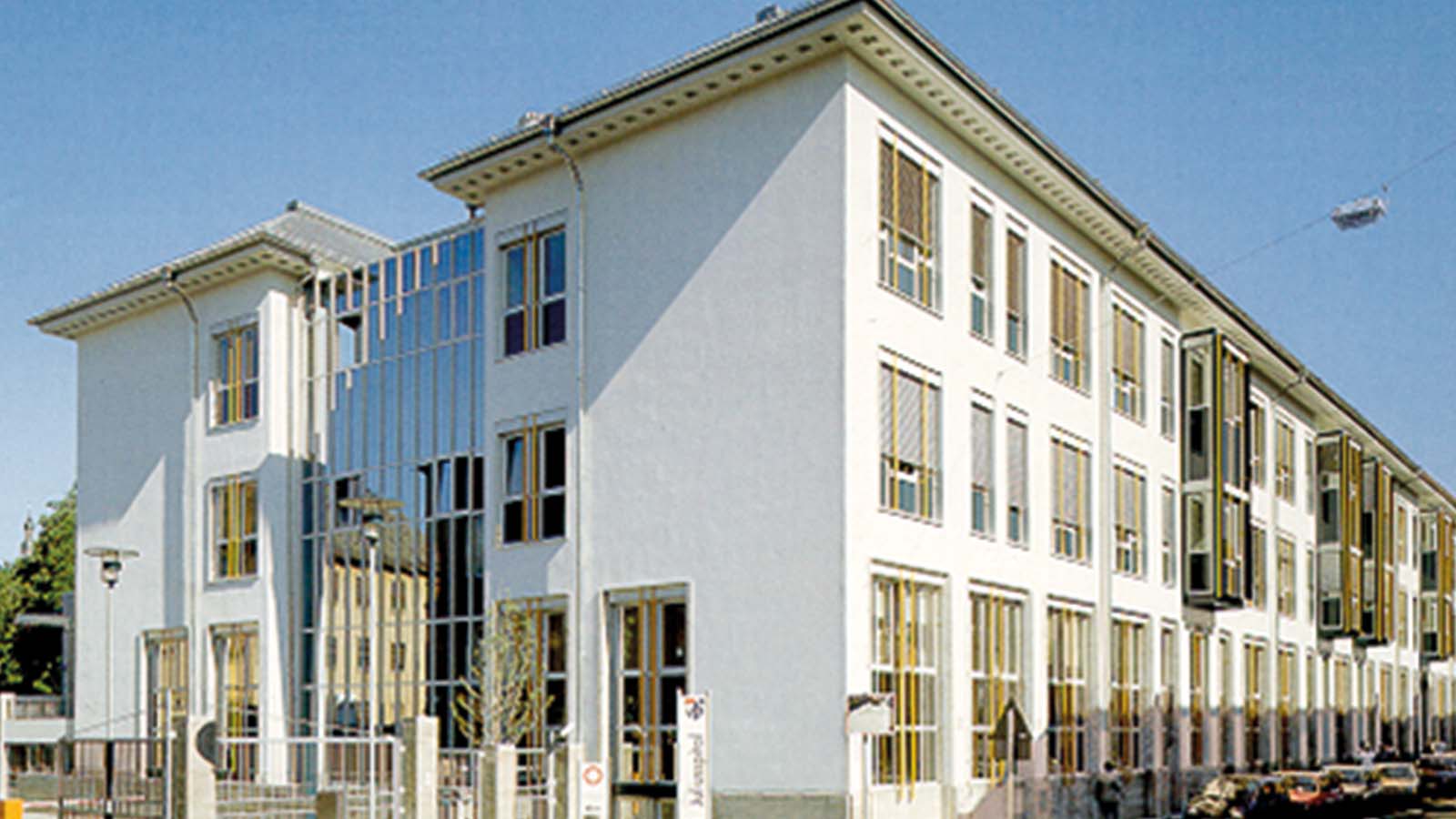 Modernes Gebäude mit Glasfassade an sonnigem Tag.