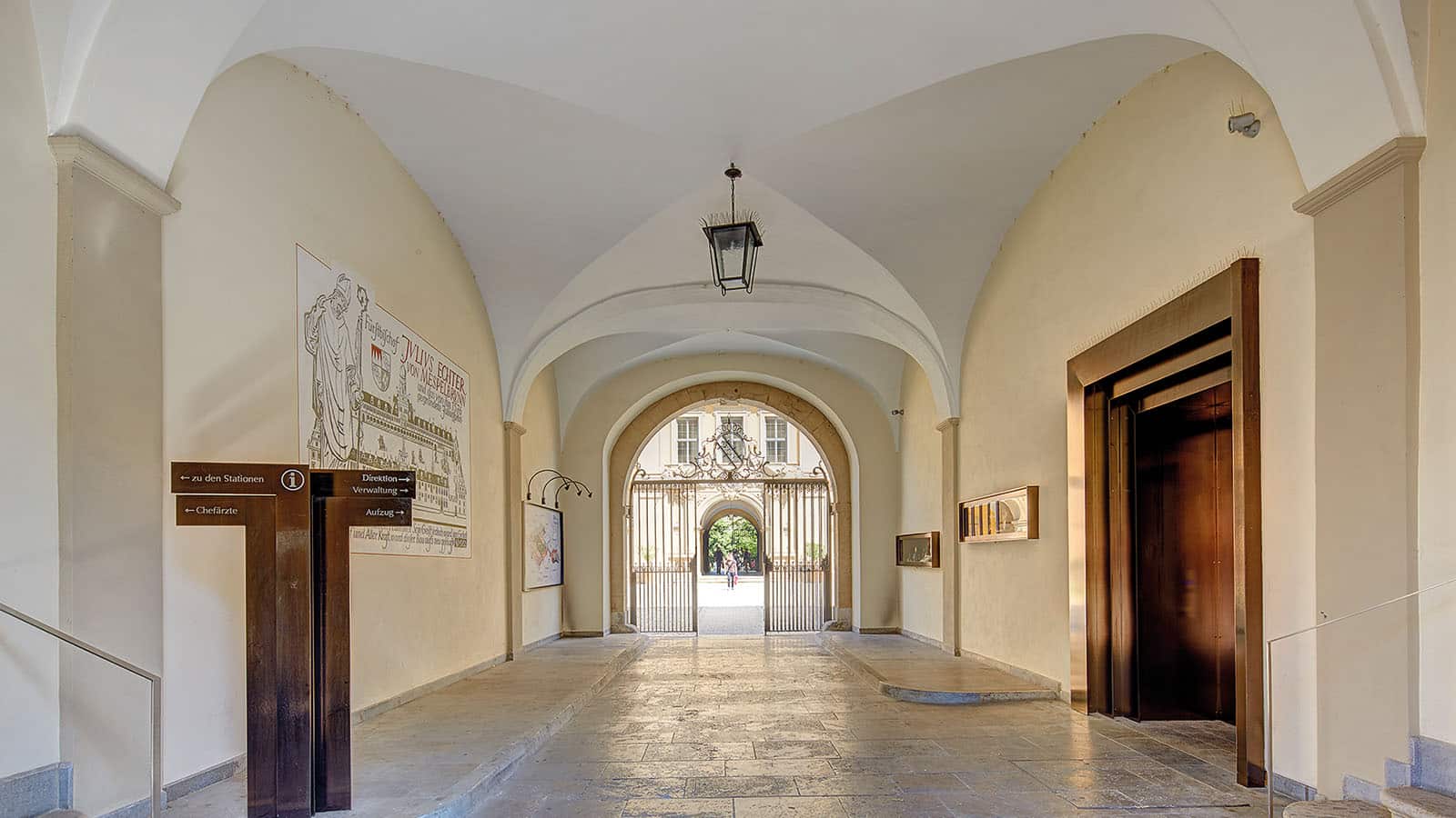 Historischer Gebäudeeingang mit Bögen und Gittertür.