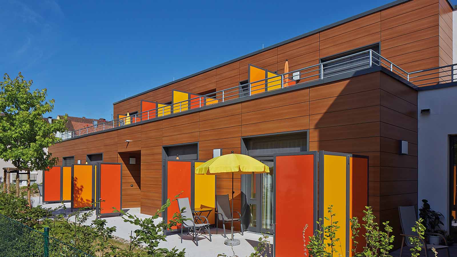 Moderne Terrasse mit bunten Paneelen und Sonnenschirm