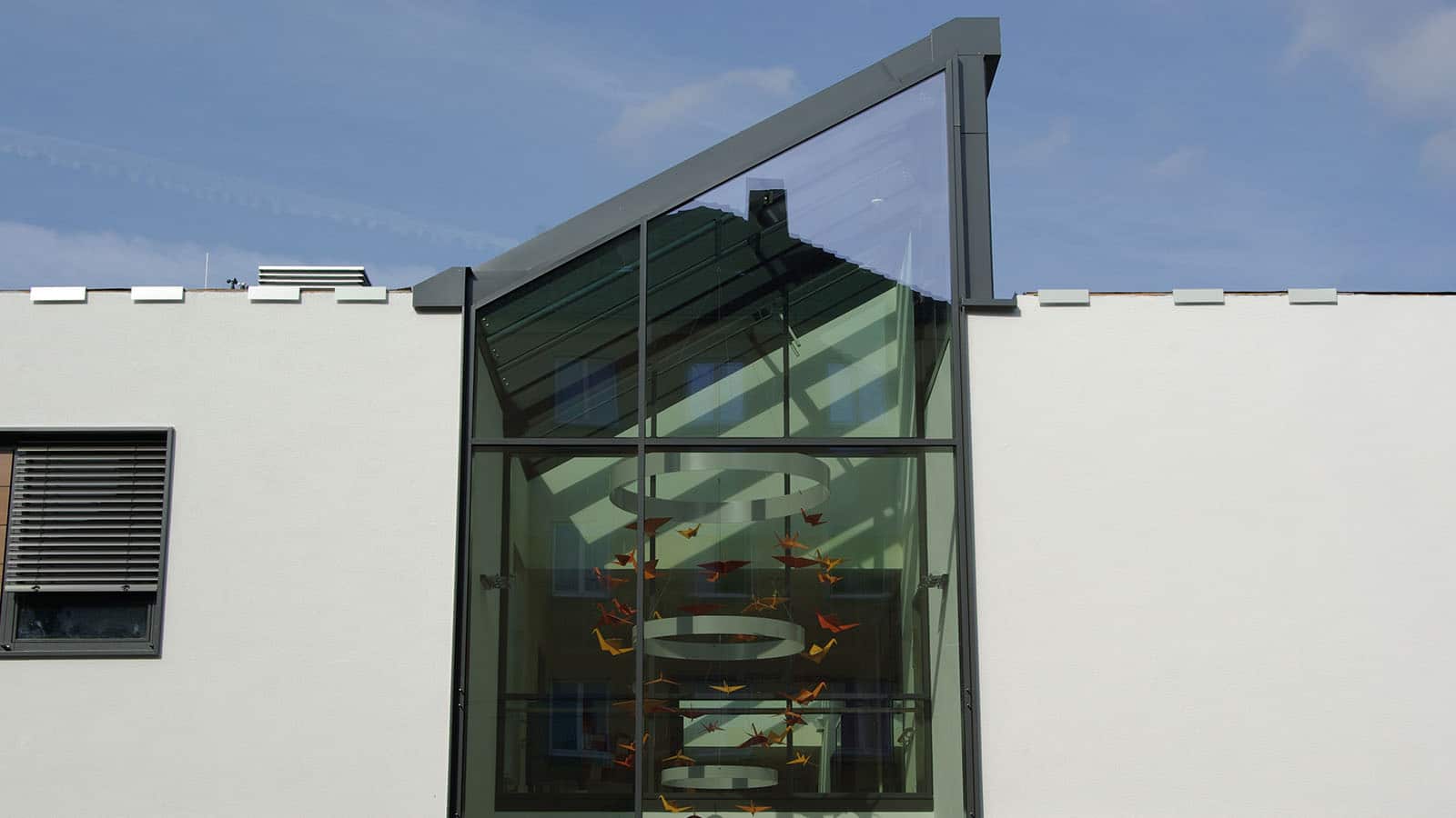 Modernes Gebäude mit großem Glasfenster und Origami-Kunst.