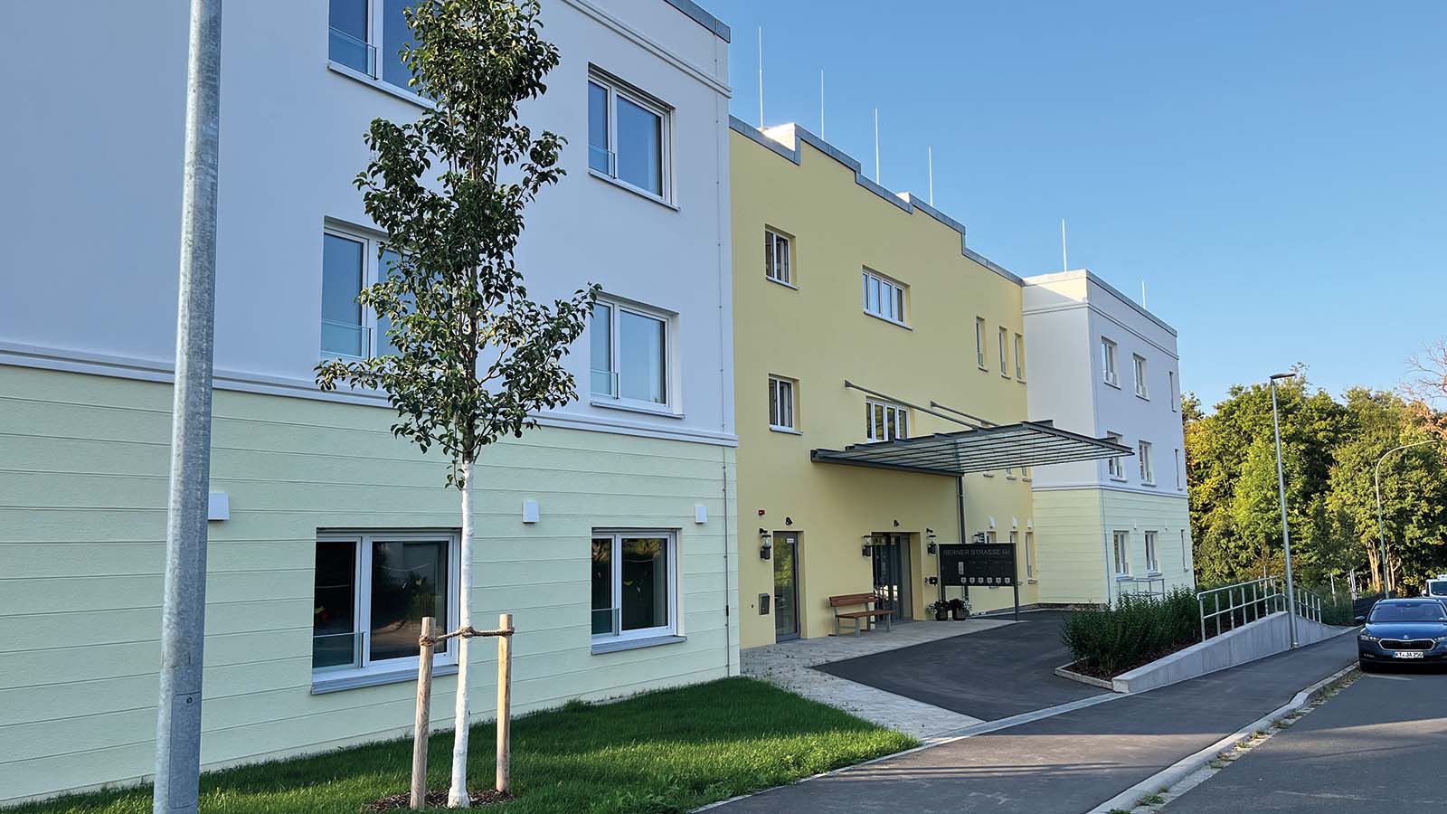 Neues Wohngebäude mit gelber Fassade und Bäumen