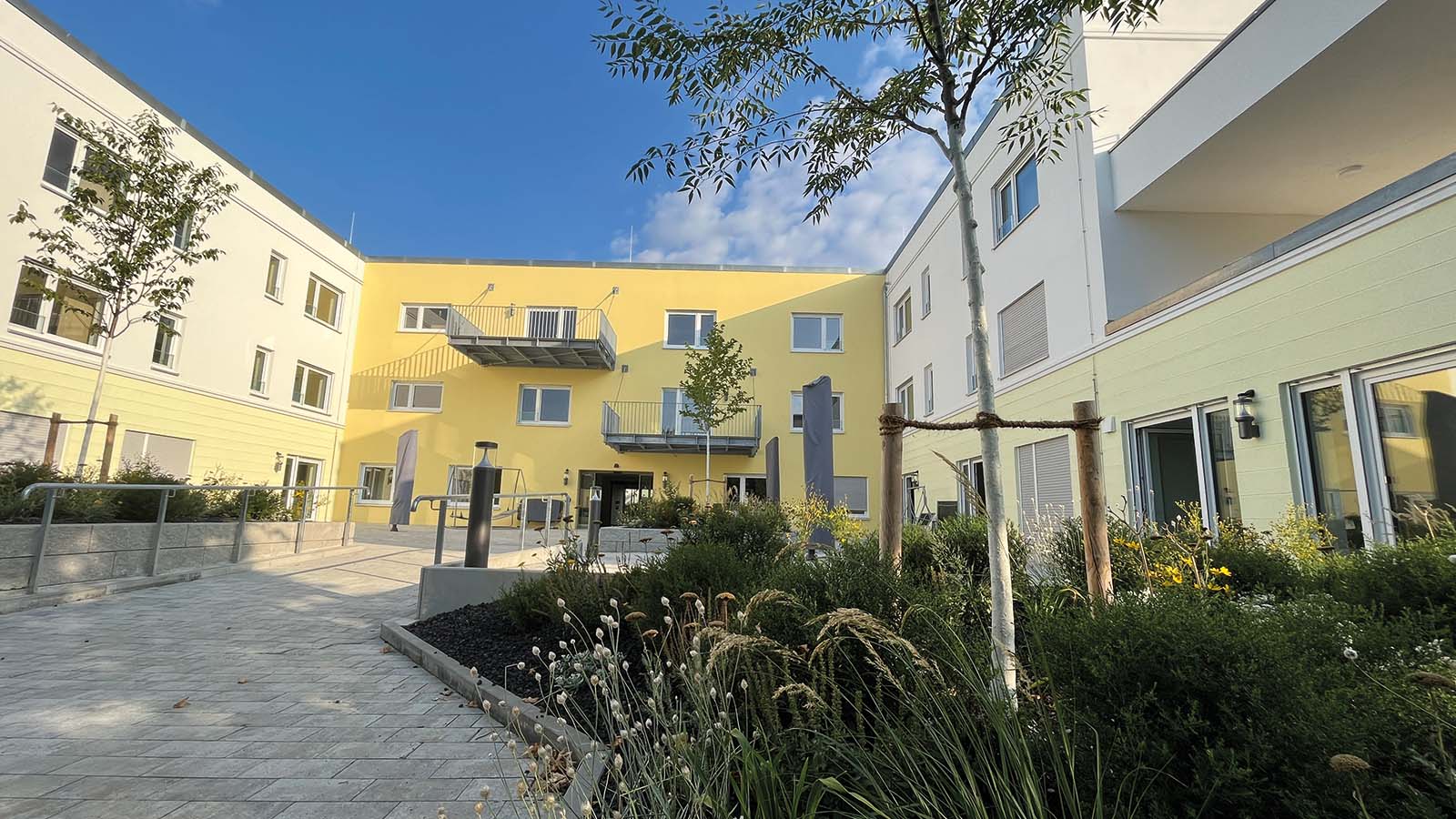 Gelbes Wohngebäude mit Garten im Innenhof.