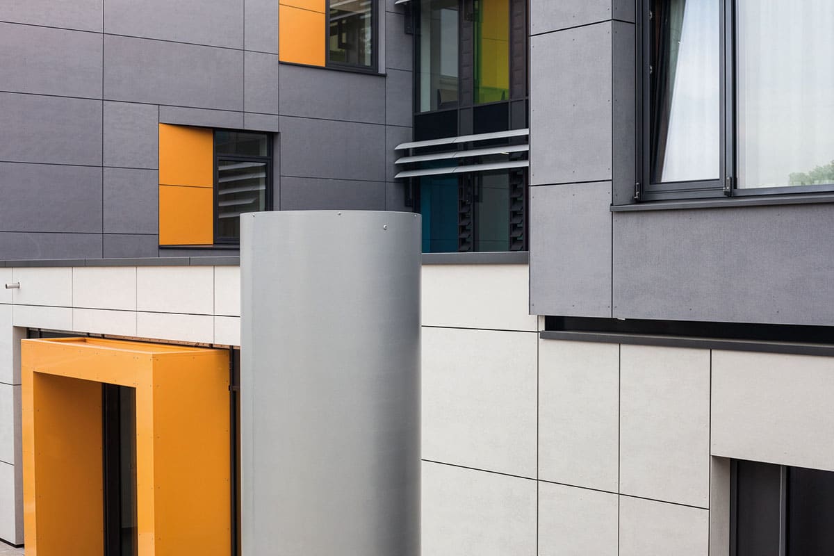 Moderne Gebäudefassade mit orangenen Akzenten und Fenstern.