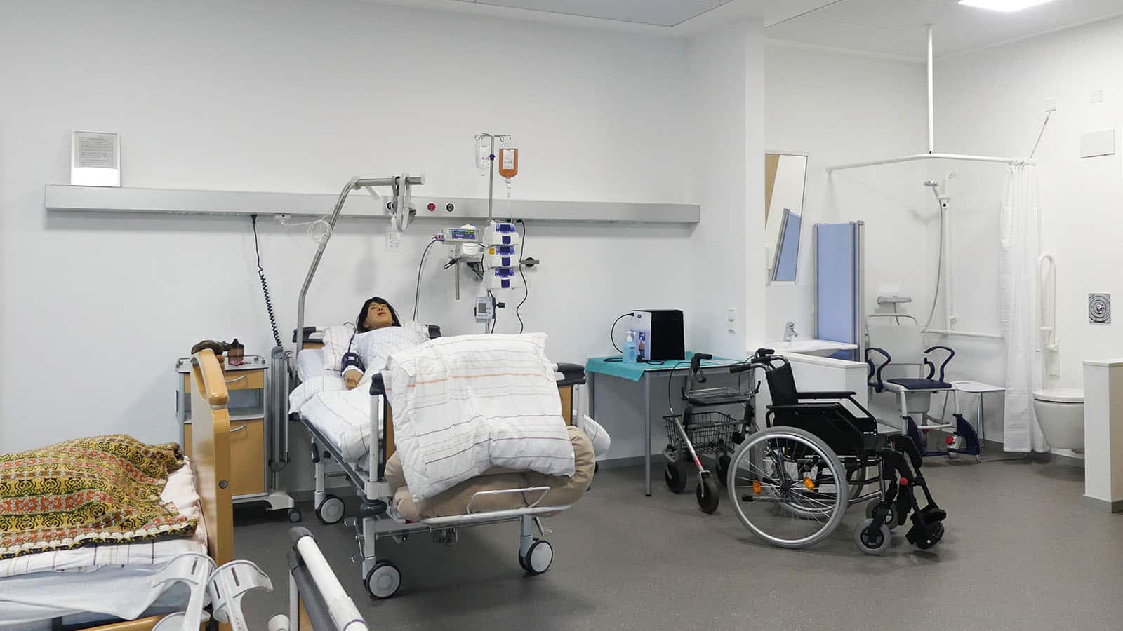 Krankenhauszimmer mit Pflegebett und Rollstuhl