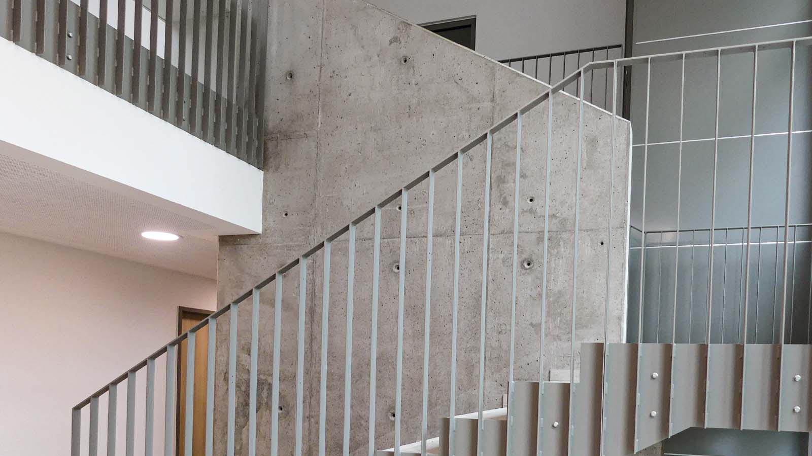 Moderne Treppe mit Betonwand und Metallgeländer