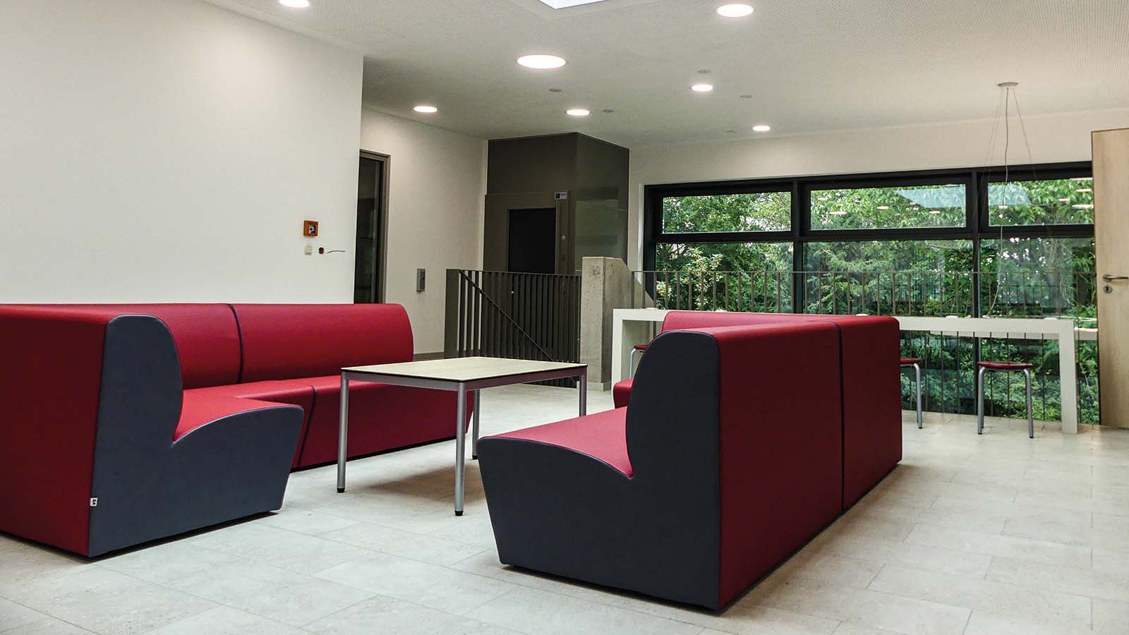 Moderne Lounge mit roten Sofas und Fensterblick.