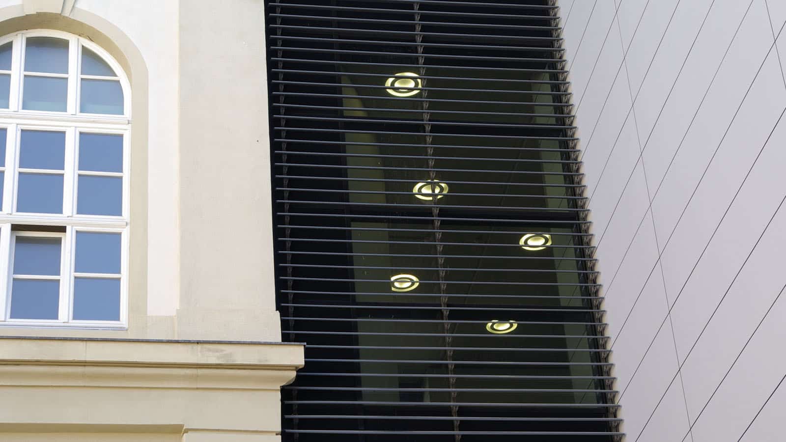 Moderne Gebäudefassade mit Fenstern und Lamellen.