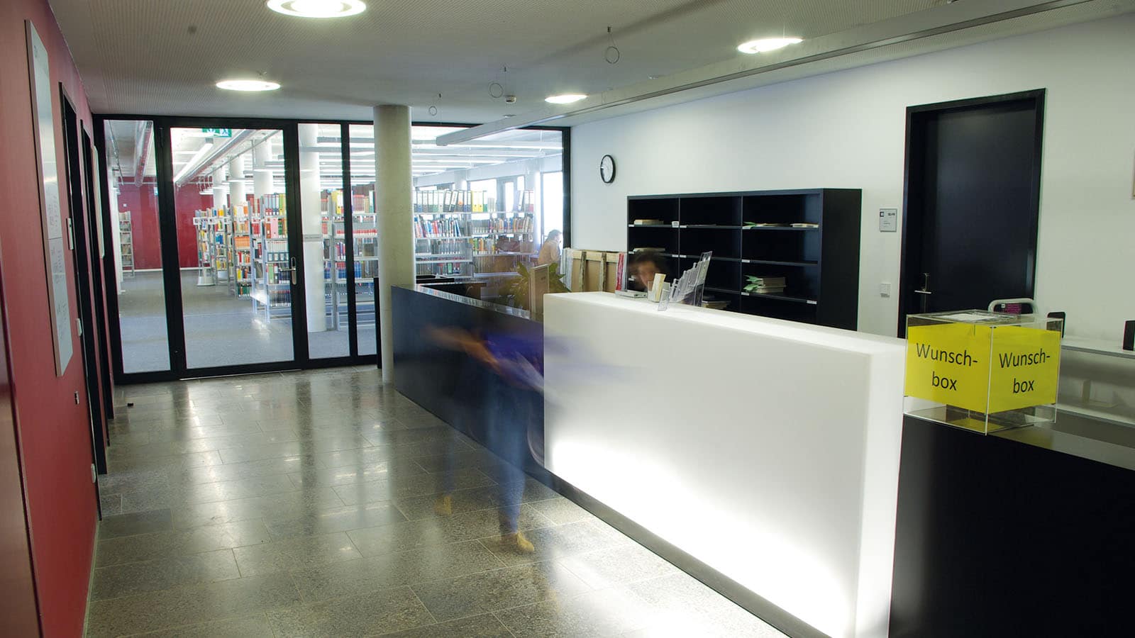Leerer Bibliothekseingang mit Informationsschalter und Wunschbox.