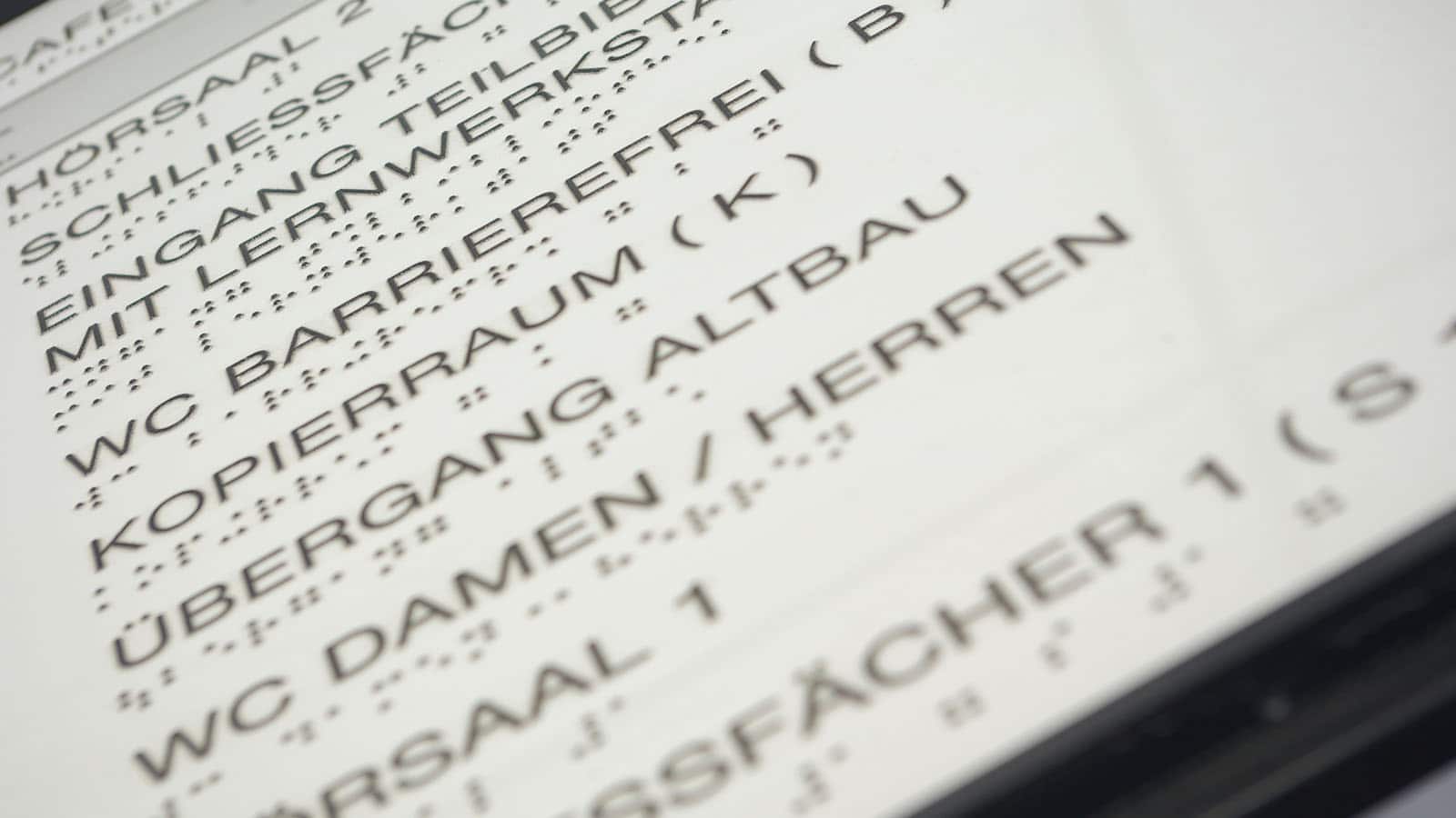 Nahaufnahme eines Schildes mit Blindenschrift.