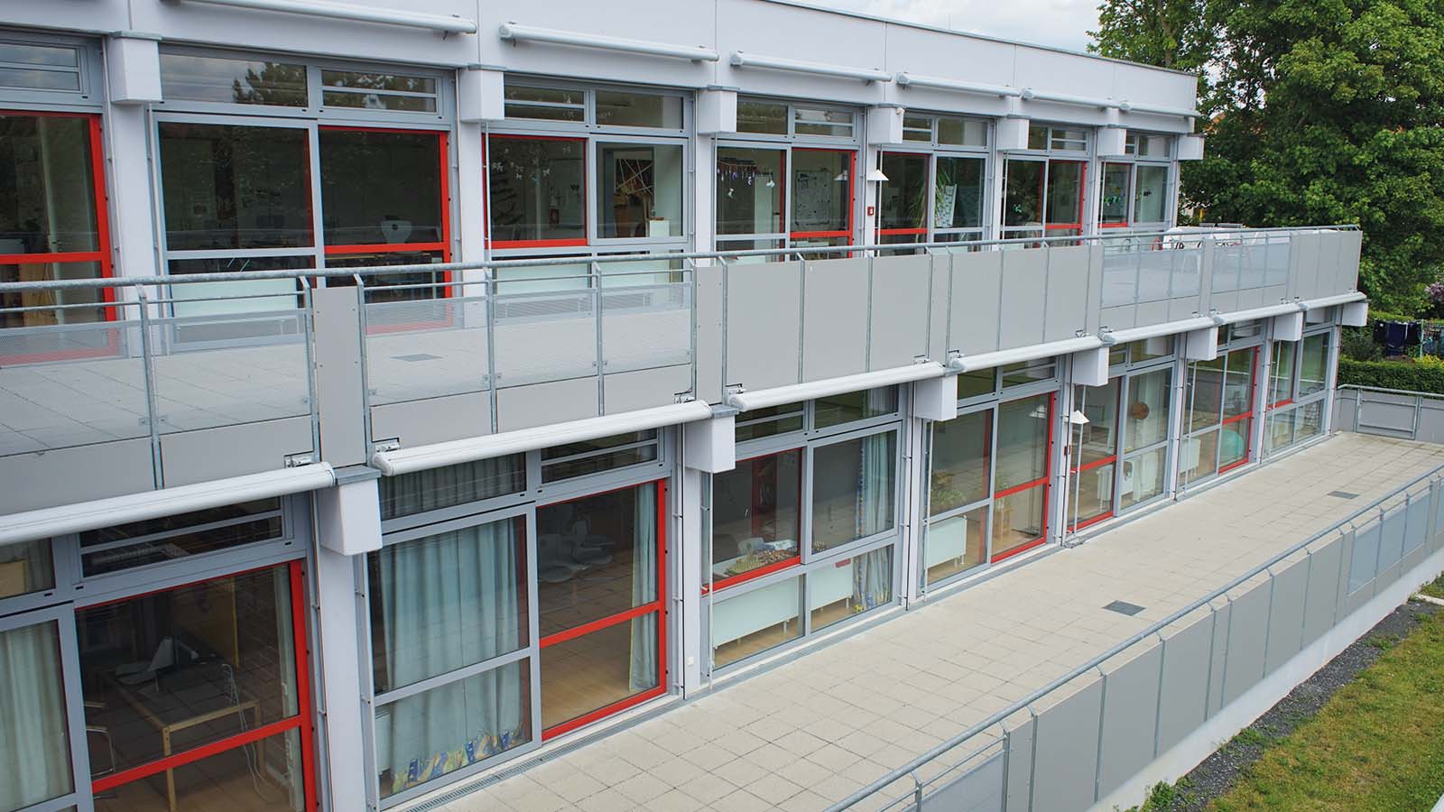 Moderner Kindergarten mit großen Fenstern und Balkon.