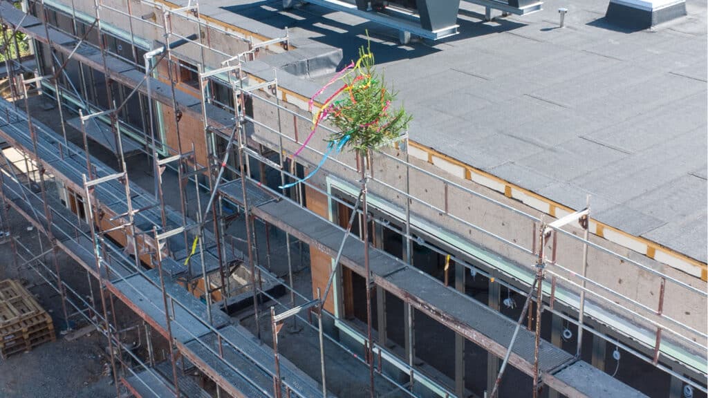 Gerüst an Neubau mit Richtfestbaum